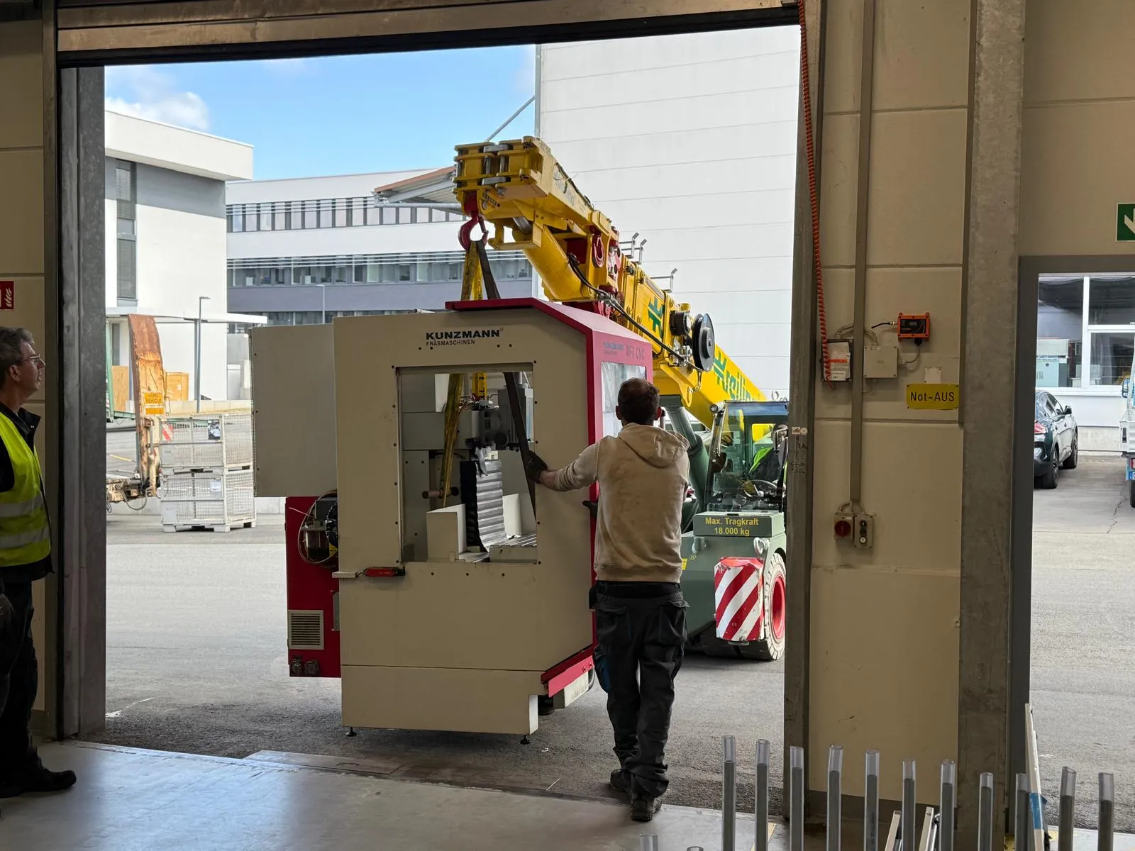 Fräsmaschine wird mit dem Autokran durch ein Hallentor gehoben