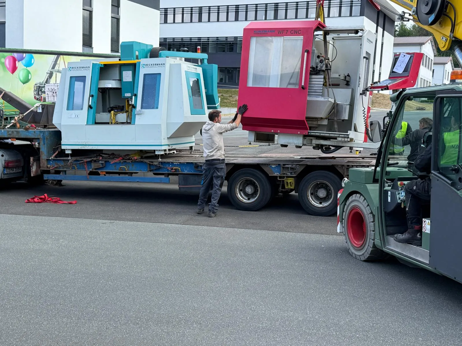 Fräsmaschine wird per Kran auf einen Tieflader gehoben