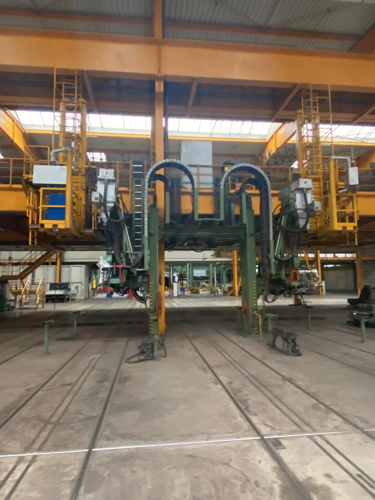 Ältere Industriehalle mit grüner Portalmaschine und Gleisen im Boden