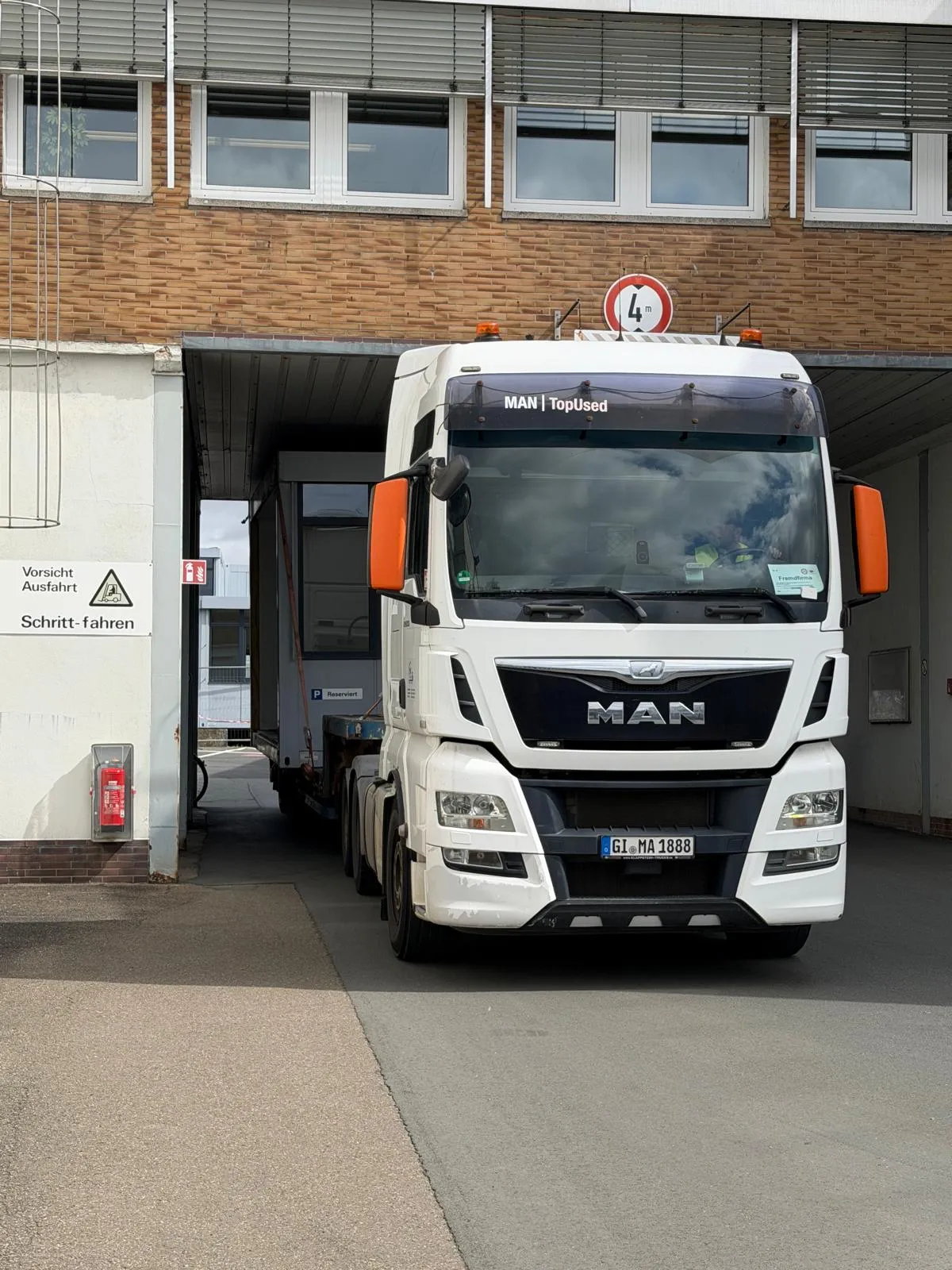 LKW mit Tieflader in der Durchfahrt eines Werksgeländes